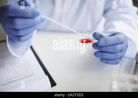 In der Nähe von Doktor in Schutzhandschuhe holding Glas mit Blutprobe und prüft es im Labor Stockfoto