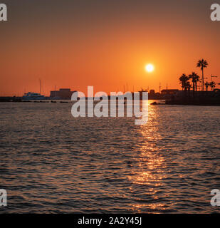 Schöne Aussicht auf den Sonnenuntergang über der alten Burg von Paphos, den Hafen und das Meer in Paphos, Zypern Stockfoto