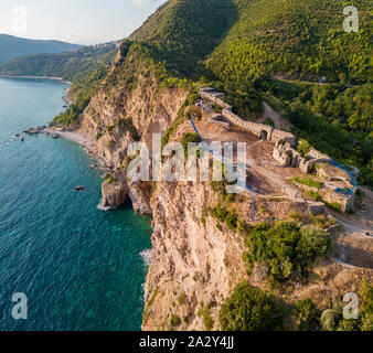 Luftaufnahme von Mogren Festung, Tvrdava Mogren, es liegt auf einem Vorgebirge Mogren entfernt. Budva. Montenegro. Zerklüftete Küste Stockfoto