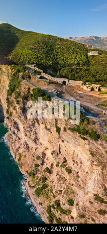 Luftaufnahme von Mogren Festung, Tvrdava Mogren, es liegt auf einem Vorgebirge Mogren entfernt. Budva. Montenegro. Zerklüftete Küste Stockfoto