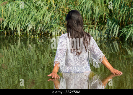 Kolumbianische Frau mit schwarzem Haar und weiße Kleidung Spaziergänge im natürlichen Wasser Stockfoto