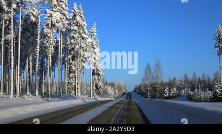 Fahren im Winter Wonderland genannt Finnland im Winter. In diesem Foto können Sie vereiste Straße und viel Schnee auf dem Boden und Wald um ihn herum. Stockfoto