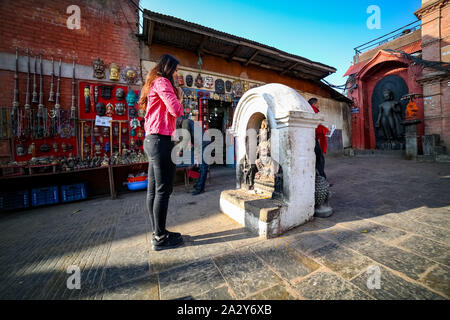 Junge Buddhistische Anhänger Mädchen beten vor einem Buddha Statue im Kloster in Nepal Swayambhunath Stockfoto