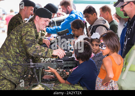 ABBOTSFORD, BC, KANADA - 11. AUG 2019: Ein Soldat der kanadischen Streitkräfte zeigt Kindern auf der Abbotsford International Airshow ein automatisches Gewehr. Stockfoto