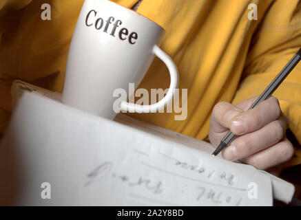 Ein Mann, der einige Berechnungen auf einem Papier während Kaffee, Studio close-up Stockfoto