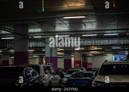 Moderne Tiefgarage im Einkaufszentrum ist voll von Autos. Industrielle städtische Interieur. Stockfoto