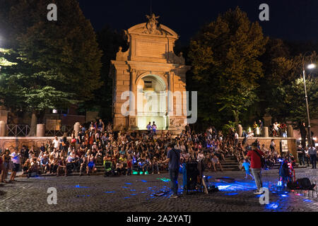 Nachtleben in Trastevere. Streetmusic vor dem Brunnen auf der Piazza Trilusso. Fontanone di Ponte Sisto in Rom bei Nacht. Eine Menge Leute sitzen Stockfoto