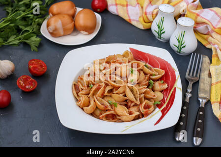 Conchiglie italienische pasta Muscheln mit Cherry Tomaten und Tomatensauce auf dunklem Hintergrund, horizontale Ausrichtung, Nahaufnahme Stockfoto