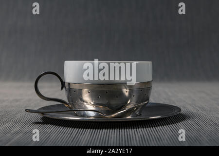 Nahaufnahme eines antiken Silver Cup mit einem Porzellan rim. und silbernen Löffel. Stockfoto