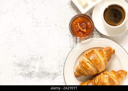 Frühstück mit Croissants. Frische knusprige Croissants und Kaffee auf einem hellen Hintergrund, Ansicht von Oben/ Stockfoto