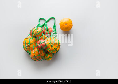 Shopping Netzbeutel mit Kürbisse und Äpfel auf Grau. Null Abfall Konzept. Platz für Text. Herbsternte. Stockfoto