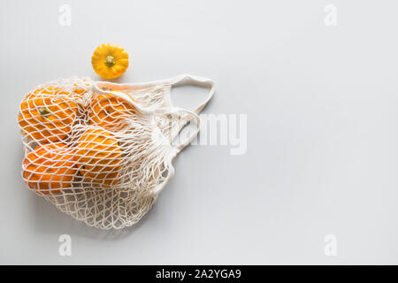 Shopping Netzbeutel mit Kürbissen auf Grau. Null Abfall Konzept. Platz für Text. Herbsternte. Stockfoto