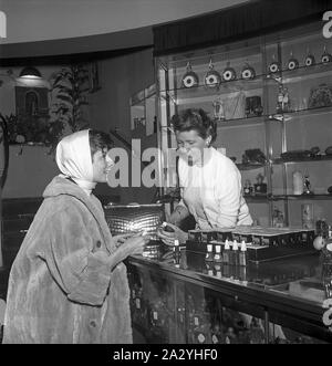 Shopping in den 1950er Jahren. Eine junge Frau in einem Parfüm Shop, wo eine Frau ist und präsentiert einige der Stores Auswahl von Kosmetika und Parfüms. Auf der Verkaufstheke Produkte von Peggy Sage ist sichtbar. Schweden 1955. Kristoffersson ref BR 26-6 Stockfoto