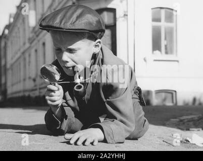 Spielen Detektiv. Ein Junge gekleidet, wie eine typische Suche Detektiv mit eine Lupe und eine Pfeife, ist draußen spielt. Schweden 1961 Stockfoto