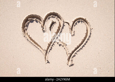 Helle, sonnige Aussicht auf zwei Herzen in sanften Sand in ein Symbol der Liebe und der tropischen Reisen verflochten auf leeren Strand Stockfoto