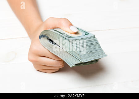 Perspektivische Ansicht der weiblichen Hand mit einem pack Geld für Holz- Hintergrund. Hundert Dollar. Geschäftskonzept. Nächstenliebe und Tipps Konzept. Stockfoto