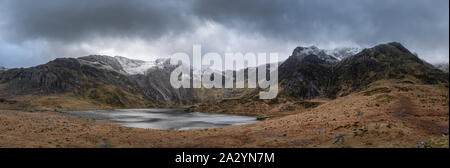 Atemberaubende dramatische Winterlandschaft Bild von Llyn Glyders Idwal und schneebedeckten Bergkette in Snowdonia Stockfoto