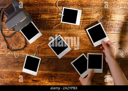Draufsicht auf leeren Fotos in die Hände und eine Kamera auf einem Holztisch. Das Konzept der angenehme Erinnerungen. Stockfoto
