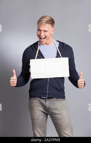 Freudiger mann Daumen hoch, der leeres Namensschild. Stockfoto