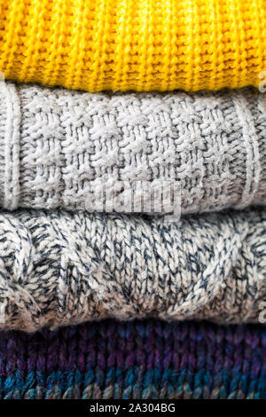 Herbst Hintergrund aus der Nähe Stapel oder Stoß von modischen gestrickt Farben wolle Kleidung oder Pullover mit verschiedenen Strickmuster. Herbst Winter Stockfoto