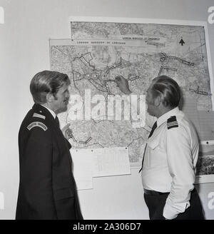 1972, historische, ein neu eingestellter Uniformierte männliche Verkehrspolizist seine Straße Bereich auf einer Karte an der Wand dargestellt von seinem Senior Officer, Lewisham, London, England, UK. Parkplatz Durchsetzung begann in Großbritannien im September 1960, als die ersten Politessen auf den Straßen von Westminster erschienen Geldstrafen für die Autofahrer im Namen der Metropolitan Police. Stockfoto