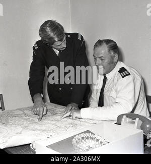 1972, historische, eine uniformierte männliche Verkehrspolizist an eine Straßenkarte mit seinem Senior Officer, Lewisham, London, England, UK. Parkplatz Durchsetzung begann in Großbritannien im September 1960, als die ersten Politessen auf den Straßen von Westminster erschienen Geldstrafen für die Autofahrer im Namen der Metropolitan Police. Stockfoto