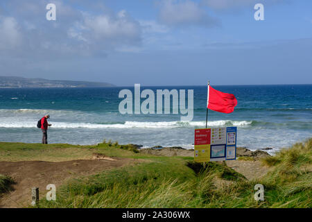 Eine rote RNLI Lifeguards Warnung Fahne über den Strand fliegen an Godrevy in Cornwall. Stockfoto