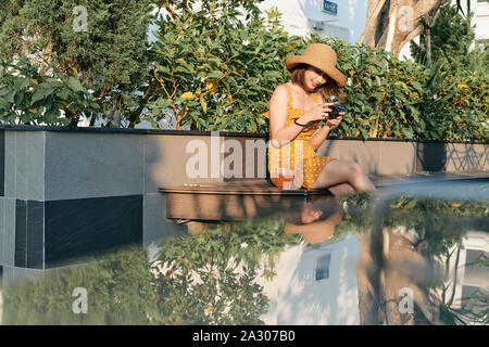 Charmant lächelnden jungen Frau im stilvollen tragen die Bilder im Park Stockfoto