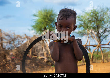 Turmi, Äthiopien - Nov 2018: Junge Hamer Stamm Kid spielen mit reifen, Omo Valley Stockfoto