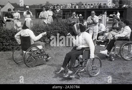 1955, historische, Stoke Mandeville Games, zwei weibliche Konkurrenten im Rollstuhl, die an die Einzäunung Wettbewerb, Stoke Mandeville Hospital, Aylesbury, Bucks, England, UK. Die Spiele waren im Jahr 1948 von Dr. Ludwig Guttmann als Versammlung der behinderten britischen WWll Veteranen mit spinalen Verletzungen begonnen und waren die Vorläufer der künftigen Paralympics. Rollstuhlfechten wurde in den Stoke Mandeville Games im Jahr 1954 eingeführt. Stockfoto