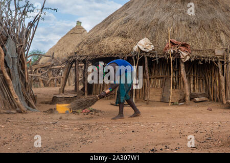 Turmi, Äthiopien - Nov 2018: Hamer Stamm Frau fegt den Hof vor dem Haus, Omo Valley Stockfoto