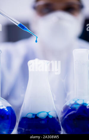 In der Nähe der weiblichen Wissenschaftler mit blauen Lösung fallen von der Pipette in einem modernen Labor. Stockfoto
