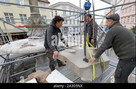 04. Oktober 2019, Mecklenburg-Vorpommern, Güstrow: Jan Hamann (L-R), Restaurtor, Johannes Victor, Steinmetz, und Dan Barsch, Restaurator, bereiten sich auf den letzten Abschnitt des oberen Wasser Schüssel an der Borwin Brunnen einstellen. Die Anpassung der vorgefertigten Abschnitt kann nur von Hand durchgeführt werden und dauert eine Woche. Das Gut hatte stark von Pyrotechnik Silvester ab 2017 bis 2018 beschädigt. Foto: Bernd Wüstneck/dpa-Zentralbild/dpa Stockfoto