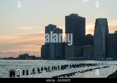 Schönen weiten Blick auf die majestätischen Sonnenuntergang hinter Downtown Finanzviertel von Manhattan Skyline am Abend Sonnenuntergang über den Hafen von New York cast Farbe Stockfoto