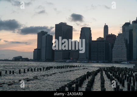 Schönen weiten Blick auf die majestätischen Sonnenuntergang hinter Downtown Finanzviertel von Manhattan Skyline am Abend Sonnenuntergang über den Hafen von New York cast Farbe Stockfoto