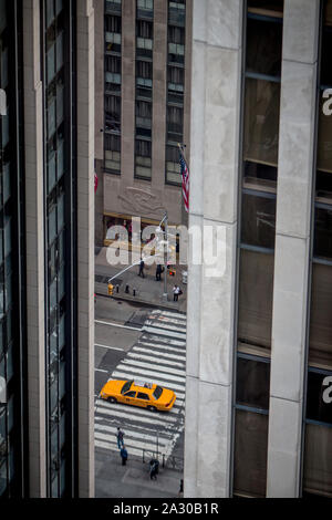 Ein yellow cab Laufwerke hinter einem pedestrial Kreuzung an der Park Avenue zwischen den Hochhäusern auf der Upper East Side von Manhattan gesehen. Stockfoto