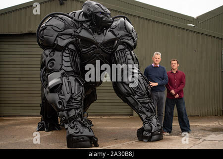 Bildhauer Lukas Kite, mit dem Vorsitzenden der britischen Eisenhütte Zentrum Clive Knowles (links), steht durch seine 12 ft Skulptur eines Gorilla Gorilla, "Apokalypse", erstellt vom Schrott Stoßstangen und Panels nur aus den letzten zehn Jahren verworfen, auf Anzeige an der britischen Schmiedearbeiten Zentrum in Telford, Shropshire. Stockfoto