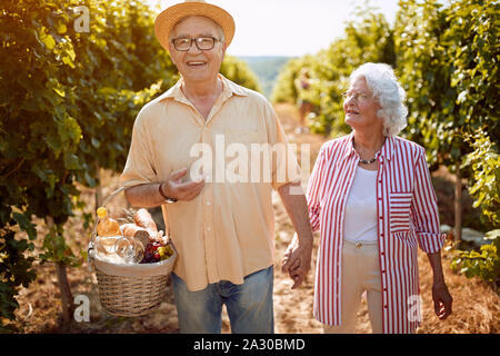 Herbst Weinberge. Wein und Trauben. Familie Tradition. Lächelnd senior Paar in zwischen den Reihen von Reben Stockfoto