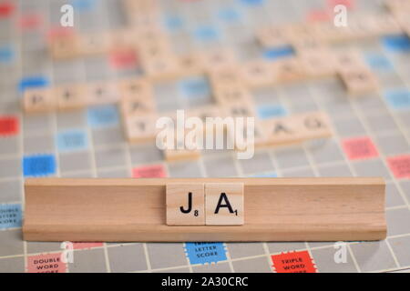 Das niederländische Wort 'Ja' (in Englisch: 'Ja') in Holz- Scrabble Fliesen auf einem Baugruppenträger. Der Hintergrund ein Vintage board, unscharf, mit Kopie Raum Stockfoto