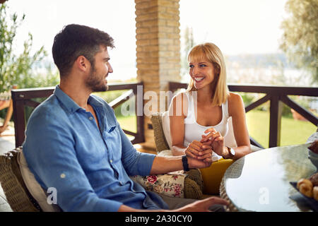 Mann und Frau in der Liebe auf der Terrasse am Tisch sitzen Stockfoto