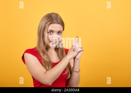 Junge blonde Mädchen im roten T-Shirt über isolierte orange Hintergrund zeigt Emotionen Stockfoto