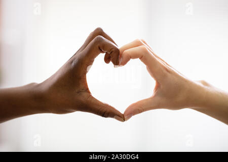 Nahaufnahme von Multirassischen's Freundin Hände sichtbar Herzform vor weißem Hintergrund Stockfoto