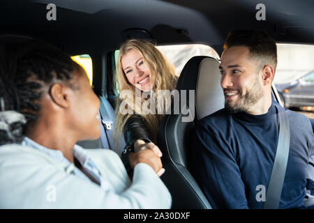 Glückliche Menschen an weibliche Freunde Hände schütteln im Auto suchen Stockfoto