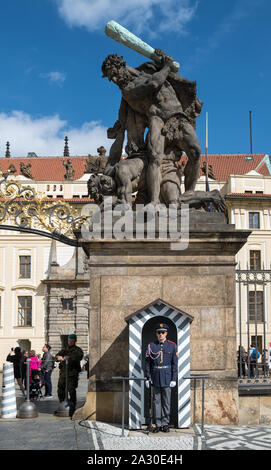 Die Prager Burg, den Hradschin, Prag, Tschechische Republik. Ein zeremonielles Guard steht im Dienst unter einem riesigen Wrestling titan Bildhauerei an der Burg Eingang Stockfoto