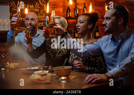 Gruppe von Freunden Fernsehen in einem Cafe hinter dem Tresen. Stockfoto