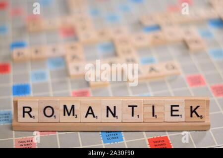 Das niederländische Wort "romantiek" (auf Deutsch: "romantische") in Holz- Scrabble Fliesen auf einem Baugruppenträger. Der Hintergrund ein Vintage board, unscharf, mit Kopie Raum Stockfoto