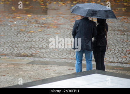 Mann und Frau stehen unter einem Sonnenschirm im Regen Stockfoto