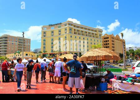 Touristen aus dem angedockten Kreuzfahrtschiffe durchsuchen die Souvenirstände entlang der Promenade direkt vor der Kreuzfahrt am Hafen von San Juan. Stockfoto