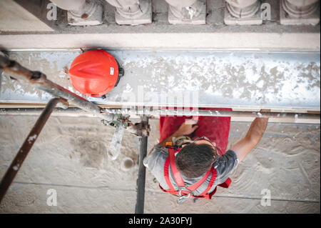 Mann Arbeiter auf Gerüst, die Arbeit an der Restaurierung der Fassade des alten Gebäudes durchführen. Reparieren und Renovieren Stockfoto