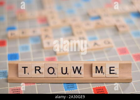 Das niederländische Wort "trouw Mich" (auf Deutsch: "Heirate mich") in Holz- Scrabble Fliesen auf einem Baugruppenträger. Der Hintergrund ein Vintage board, unscharf, mit Kopie Raum Stockfoto